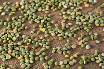 Green peas on rustic wooden background, close-up, top view, selective focus.