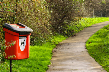 Dog waste bin by a path in a park.