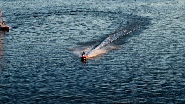 Man riding a jet ski on the sea, turns and brakes on the water