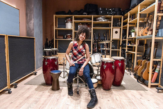 Cheerful woman sitting near drums