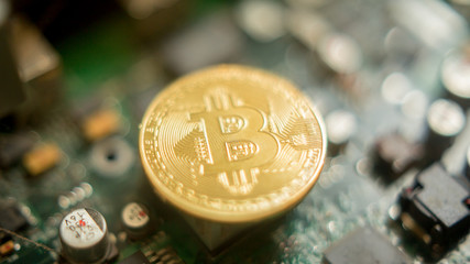 Bitcoin mining process - gold coin on computer circuit board with bitcoin processor and microchips. Electronic currency, internet finance rypto currency concept. Golden Bitcoin Cryptocurrency