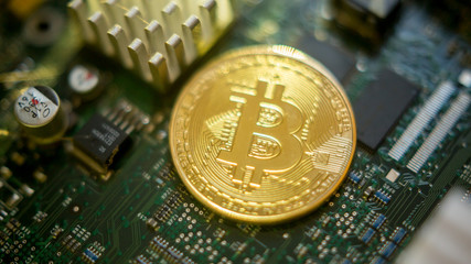 Bitcoin mining process - gold coin on computer circuit board with bitcoin processor and microchips. Electronic currency, internet finance rypto currency concept. Golden Bitcoin Cryptocurrency