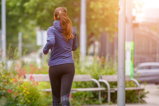 Young fitness woman jogging in park in the sunny morning. Image with copy space
