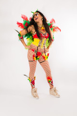 Very fit young hispanic woman in Carnaval costume and athletic shoes posing on clean white background
