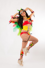 Very fit young hispanic woman in Carnaval costume and athletic shoes posing on clean white background