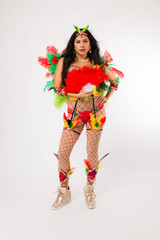 Very fit young hispanic woman in Carnaval costume and athletic shoes posing on clean white background