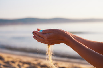 Sand flowing through the woman's hands on the beach