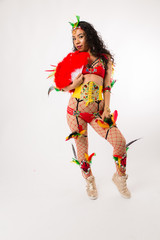 Fit young hispanic woman in Carnaval costume and athletic shoes posing on clean white background