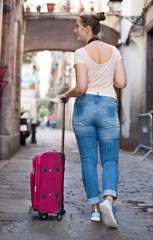 Fototapeta na wymiar Tourist girl taking a walk with travel bag