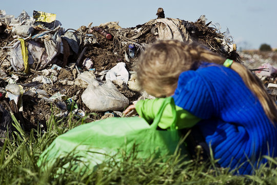 A beggar child bent his head on a garbage bag in a garbage dump