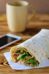 Shaurma chicken roll in a pita with fresh vegetables on wooden background