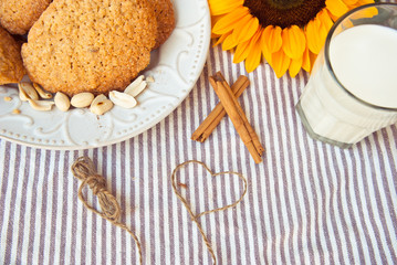 Fototapeta na wymiar Romantic breakfast with homemade oatmeal cookies and glass of milk and decorated with sunflower.