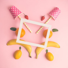 High angle view of fruits, paper cups with drinking straws and photo frame abstract.