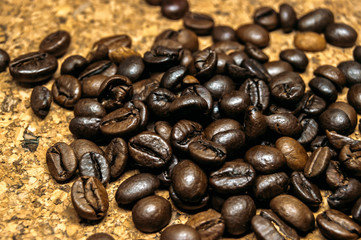 Fresh black coffe beans on cork table