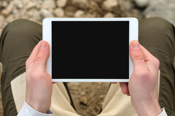Digital tablet computer with isolated screen in male hands over cafe background - table, cup of coffee.