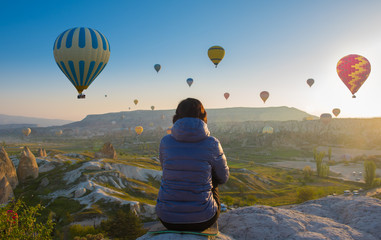 woman on top of Cappadocia hill in early morning sunrise, when balloons fly. Romantic Cappadocia scene, Turkey