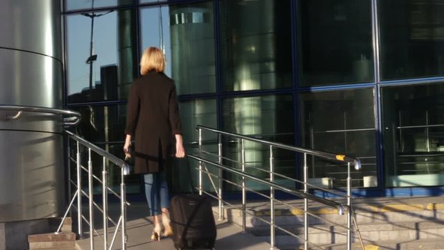 Business woman entering airport holding luggage to departure. Business trip