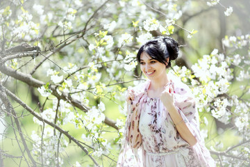 Beautiful brunette girl in a spring blooming garden. 