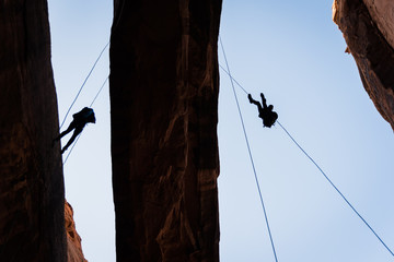 People rappelling off of Morning Glory Arch in Moab, Utah. 