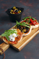 Delicious tapas set. Small sandwiches with goat cheese, chopped olives and nuts, cured tomato and roasted bell pepper.