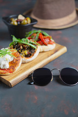 Delicious tapas set. Small sandwiches with goat cheese, chopped olives and nuts, cured tomato and roasted bell pepper.