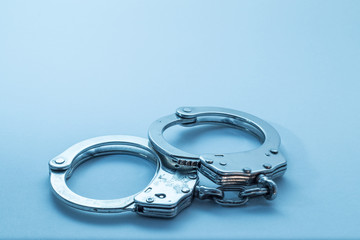 Handcuffs with signs of usage on blue background