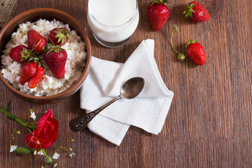 Village breakfast of homemade cottage cheese with strawberry, glass of milk with bunch of poppy flower