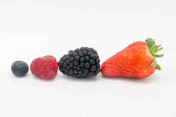 Different berries in a row against a white background
