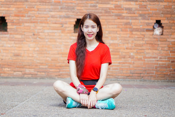 Cute girl with white skin, wearing red shirt, sitting with red brick ancient background.