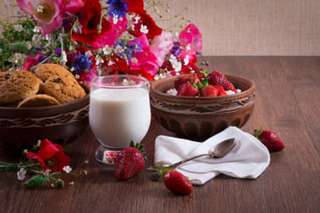 Breakfast of homemade cottage cheese with strawberry, glass of milk and bunch of poppy flower. Romantic mood