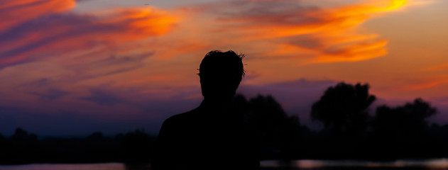 Silhouette of a man at sunset with his hands up. Concept of victory