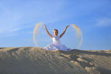 Mała dziewczynka w białej sukni, w pierwszym dniu komuni, na piaszczystej wydmie. - obrazy, fototapety, plakaty