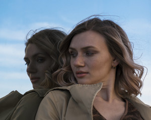 Attractive Young Blonde Woman in Trench walking in City Mirrors with Vintage Suitcase