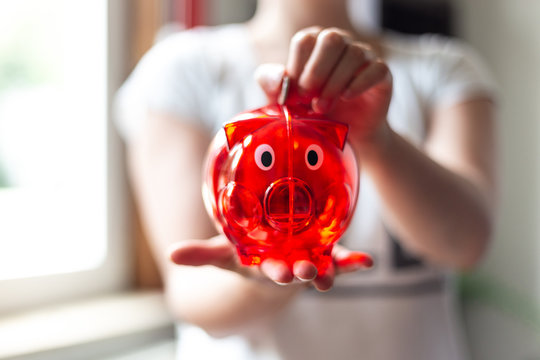 Geld in ein rotes Sparschwein werfen