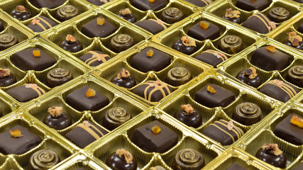 Many assorted chocolates in golden containers ready for sale.