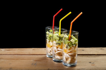 on a wooden table are three glasses of fruit for a fruit cocktail