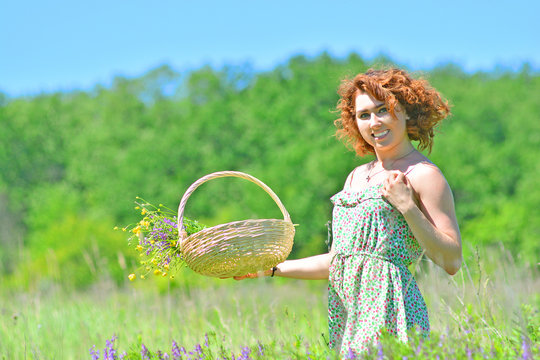 Summer background with a beautiful cheerfull girl with bouquet of flowers in bascket