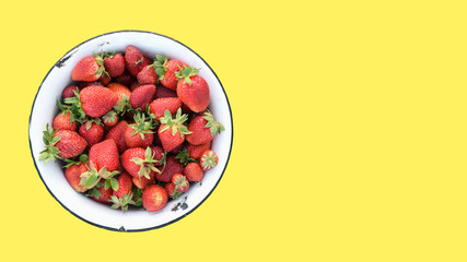 Retro bowl of fresh strawberries from own field, isolated on a yellow background, top view, copy space for text