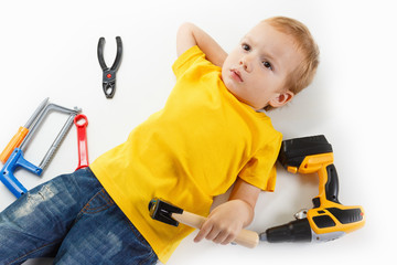 Top view, little kid lying with hands behind his head on white background and many colorful toys...