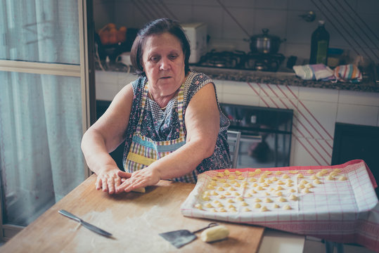 italian woman make homemade pasta gnocchi on wood board. Typical senior woman from south of Italy makes pasta from dough 