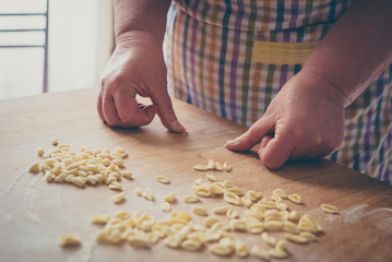 Process of production of pasta. woman hands make fresh pasta on wood board kitchen table