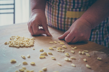 Process of production of pasta. woman hands make fresh pasta on wood board kitchen table
