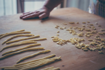 Process of production of pasta. woman hands make fresh pasta on wood board kitchen table