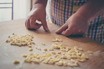 Process of production of pasta. woman hands make fresh pasta on wood board kitchen table