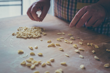 Process of production of pasta. woman hands make fresh pasta on wood board kitchen table