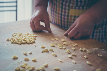 Process of production of pasta. woman hands make fresh pasta on wood board kitchen table