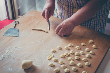 woman make homemade pasta gnocchi on wood board. Typical senior woman from south of Italy makes...