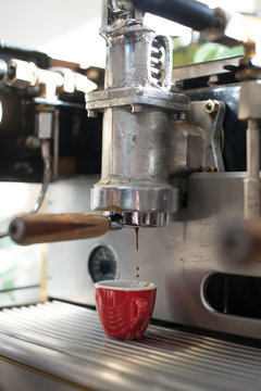 Espresso machine dripping into red espresso cup