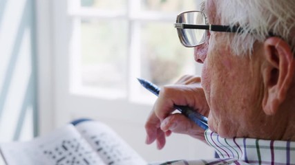 Senior man doing crossword, close up - Powered by Adobe