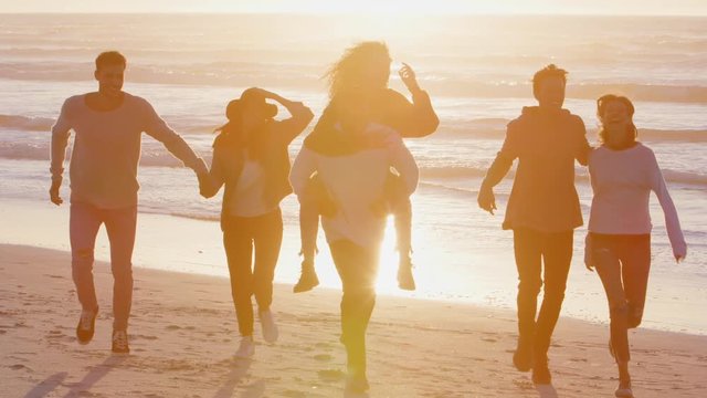 Group Of Friends Having Fun Running Along Winter Beach Together